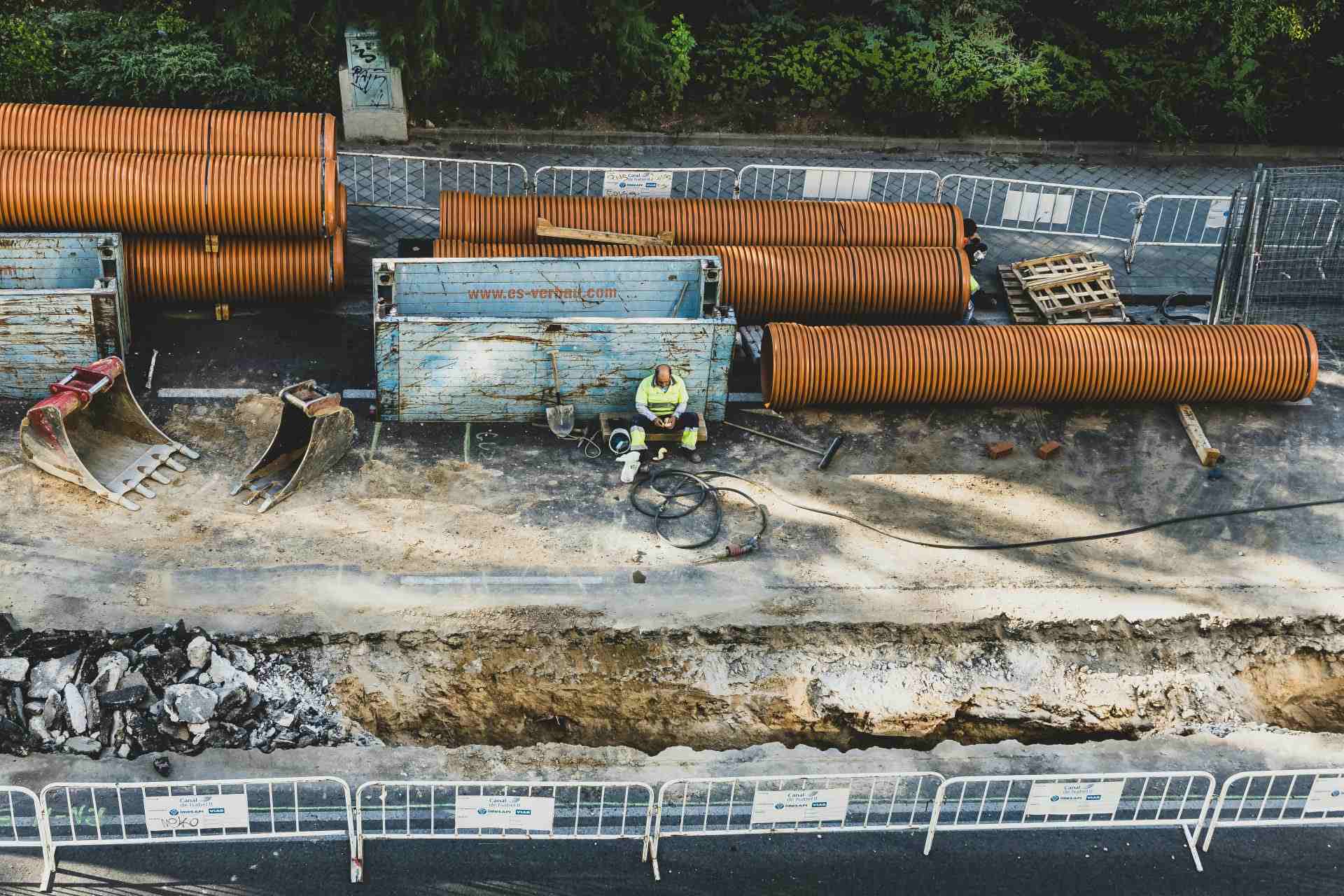 Ein Bauarbeiter macht eine Pause auf einer Baustelle in Madrid, umgeben von Geräten und Baumaterialien.