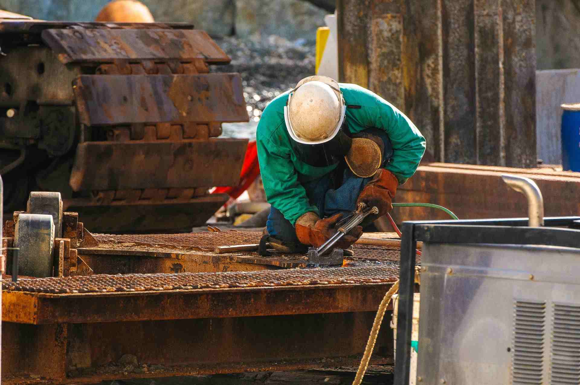 Ein Schweißer in Schutzkleidung arbeitet im Freien auf einer Baustelle.
